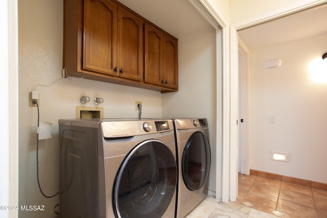 washroom with cabinets, light tile patterned floors, and washer and clothes dryer