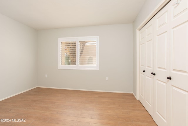 unfurnished bedroom featuring light wood-type flooring and a closet