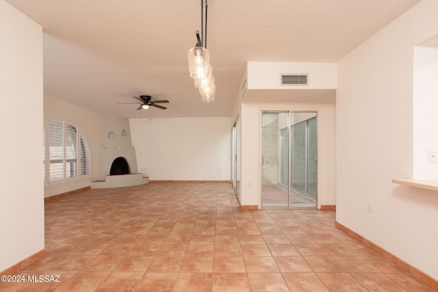 unfurnished living room with ceiling fan, light tile patterned flooring, and a fireplace