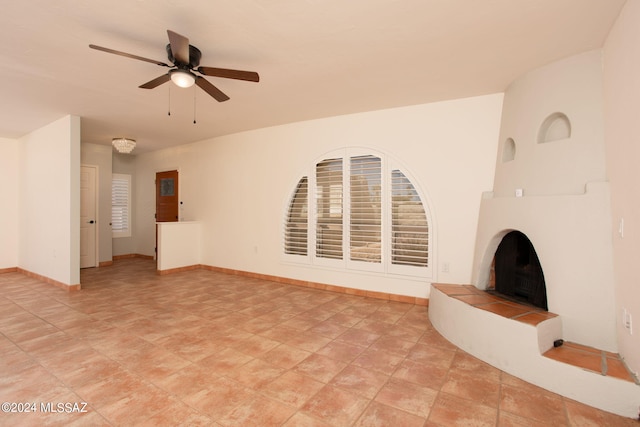 unfurnished living room featuring ceiling fan and a fireplace