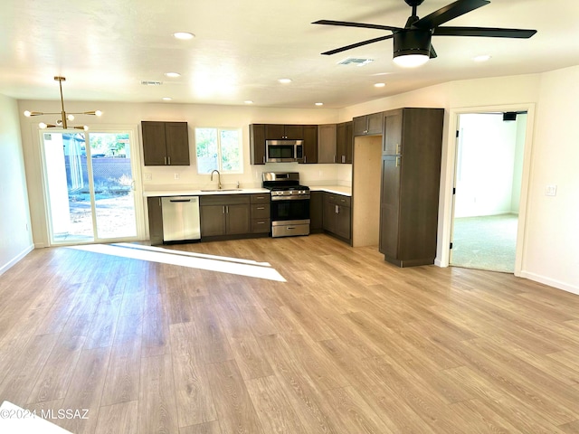 kitchen with ceiling fan with notable chandelier, sink, appliances with stainless steel finishes, decorative light fixtures, and light hardwood / wood-style floors