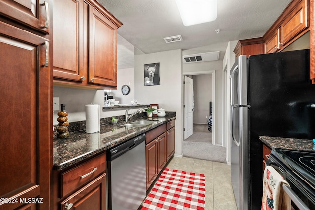 kitchen featuring sink, dark stone countertops, light tile patterned floors, a textured ceiling, and stainless steel appliances