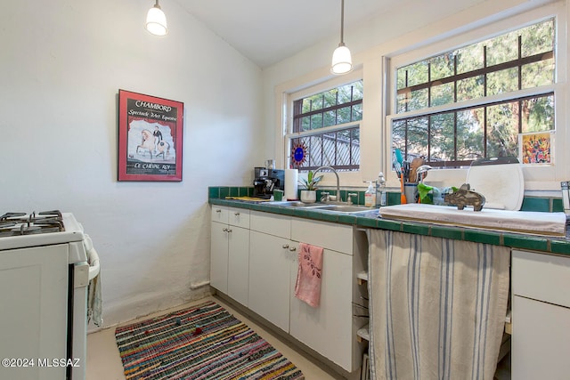 kitchen featuring white range, vaulted ceiling, sink, decorative light fixtures, and white cabinets