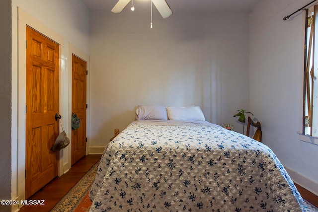 bedroom with multiple windows, dark hardwood / wood-style flooring, and ceiling fan