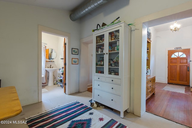 hall with light hardwood / wood-style floors, vaulted ceiling, sink, and a chandelier