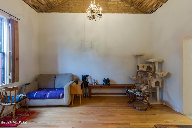 living area featuring hardwood / wood-style flooring, a notable chandelier, and lofted ceiling