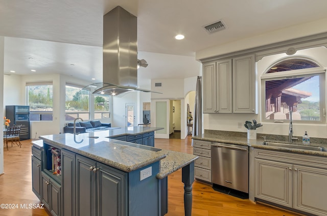 kitchen with island range hood, open floor plan, stainless steel dishwasher, light wood-style floors, and a sink