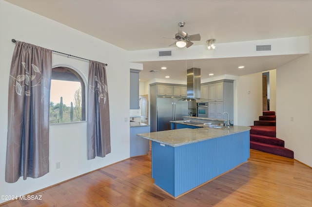 kitchen featuring kitchen peninsula, oven, island exhaust hood, ceiling fan, and light hardwood / wood-style floors