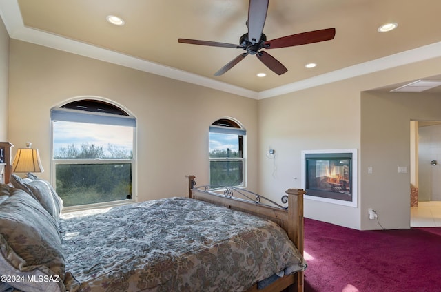 carpeted bedroom featuring ornamental molding, recessed lighting, a glass covered fireplace, and ceiling fan