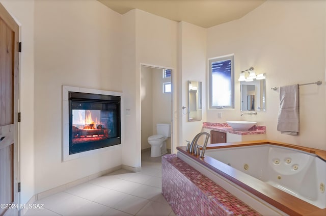 bathroom with tile patterned flooring, toilet, visible vents, a whirlpool tub, and a glass covered fireplace