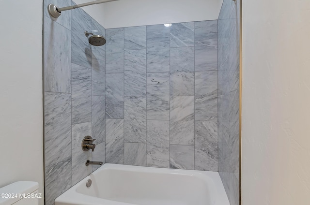 bathroom featuring tiled shower / bath combo and toilet