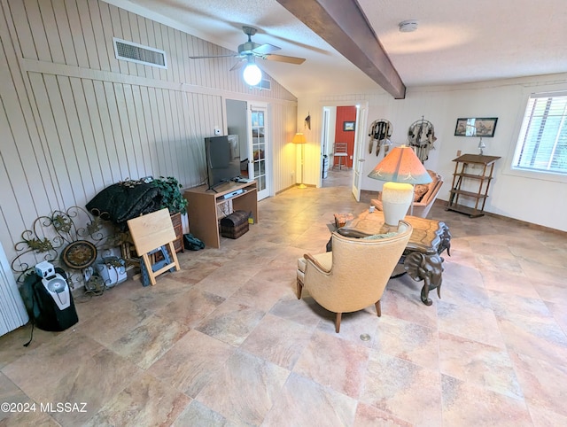 living room with beamed ceiling, ceiling fan, and wood walls