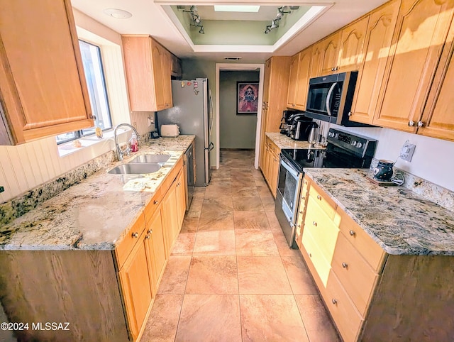 kitchen featuring light stone counters, a raised ceiling, sink, and appliances with stainless steel finishes