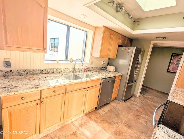 kitchen with light stone countertops, appliances with stainless steel finishes, light brown cabinetry, and sink