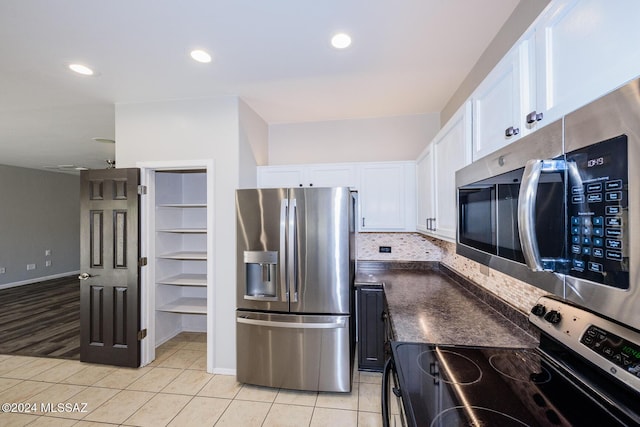 kitchen featuring appliances with stainless steel finishes, light tile patterned floors, white cabinetry, and backsplash