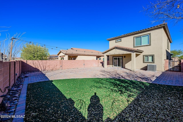 rear view of property featuring central air condition unit, a yard, and a patio