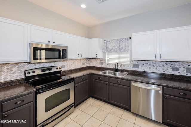 kitchen with sink, stainless steel appliances, white cabinets, backsplash, and light tile patterned flooring