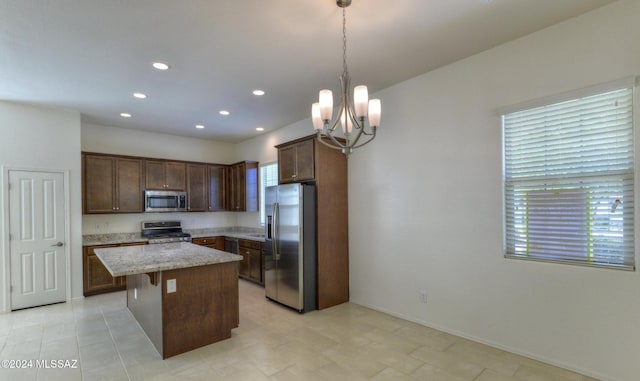 kitchen with a center island, an inviting chandelier, a kitchen breakfast bar, decorative light fixtures, and appliances with stainless steel finishes