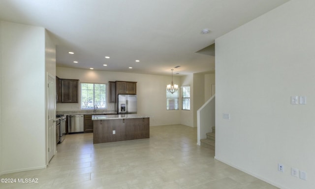 kitchen featuring sink, stainless steel appliances, a chandelier, decorative light fixtures, and a kitchen island