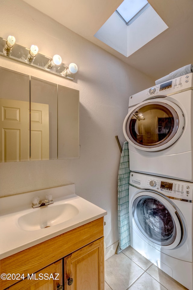 clothes washing area featuring light tile patterned floors, a skylight, stacked washer / drying machine, and sink