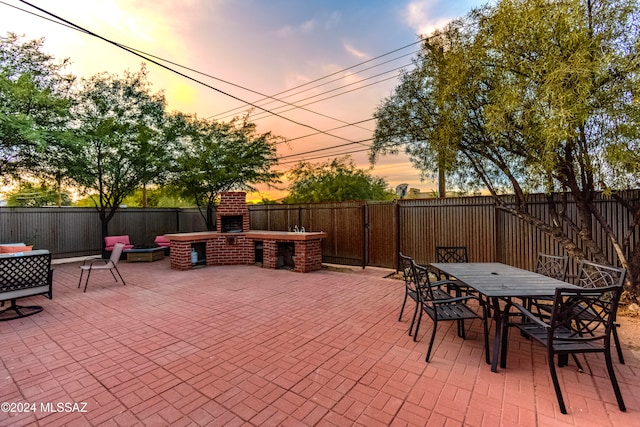 patio terrace at dusk featuring an outdoor brick fireplace