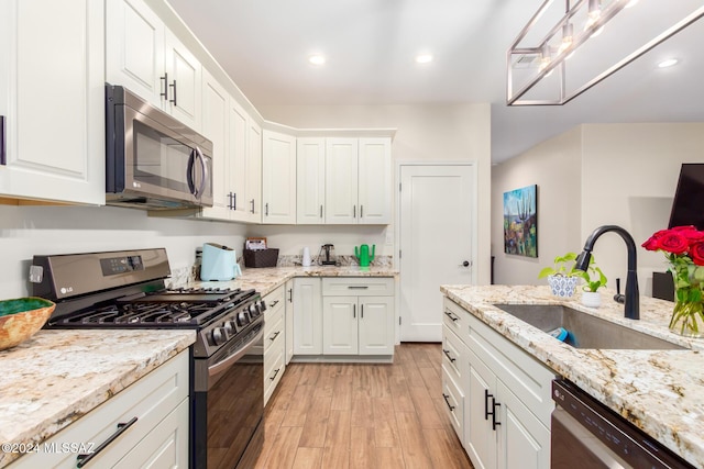 kitchen with light stone counters, stainless steel appliances, sink, light hardwood / wood-style flooring, and white cabinetry