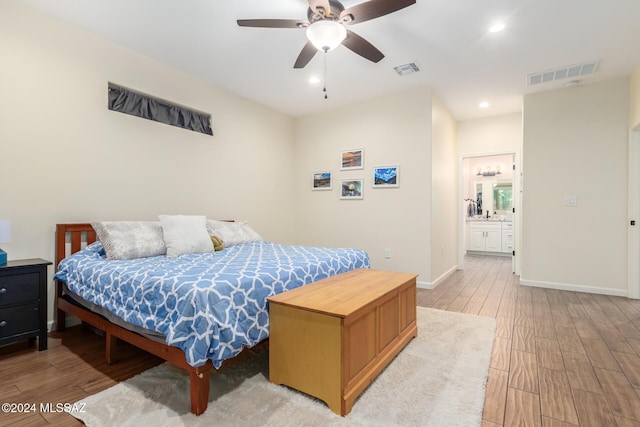 bedroom featuring light wood-type flooring, ceiling fan, and connected bathroom