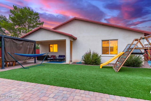 back house at dusk with a yard and a patio