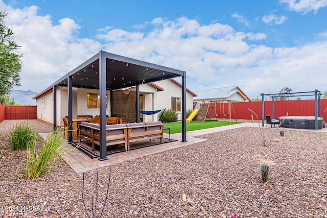 back of house with outdoor lounge area, a hot tub, a playground, a wooden deck, and a patio area