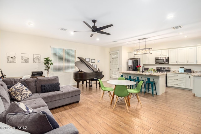 living room with light hardwood / wood-style floors, ceiling fan, and sink