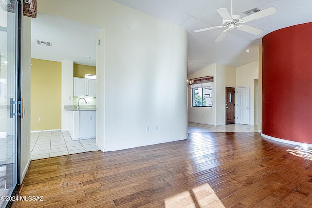 unfurnished living room featuring lofted ceiling, sink, light hardwood / wood-style floors, and ceiling fan