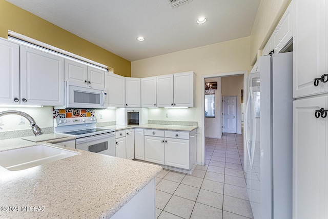 kitchen with sink, white appliances, light tile patterned floors, and white cabinets