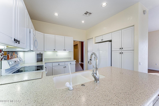 kitchen with sink, white cabinetry, electric range, white fridge, and light stone countertops