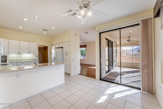 kitchen featuring light tile patterned flooring, white cabinetry, ceiling fan, white appliances, and light stone countertops