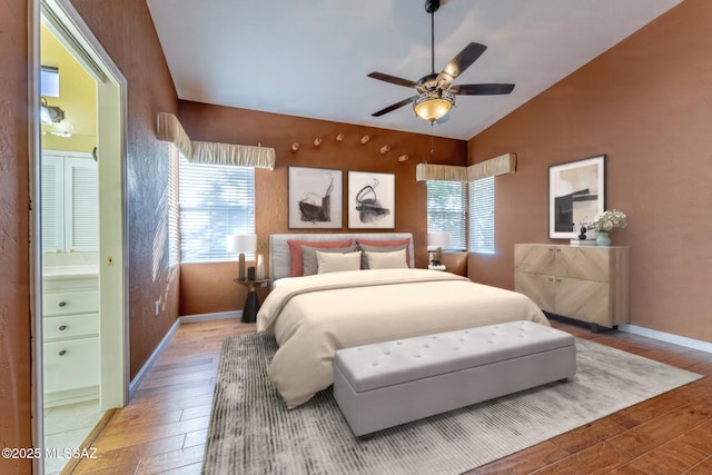 bedroom featuring lofted ceiling, connected bathroom, hardwood / wood-style flooring, and ceiling fan