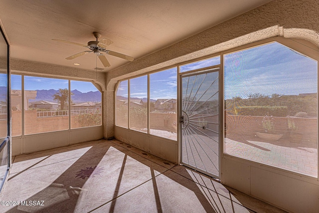 unfurnished sunroom with a mountain view and ceiling fan