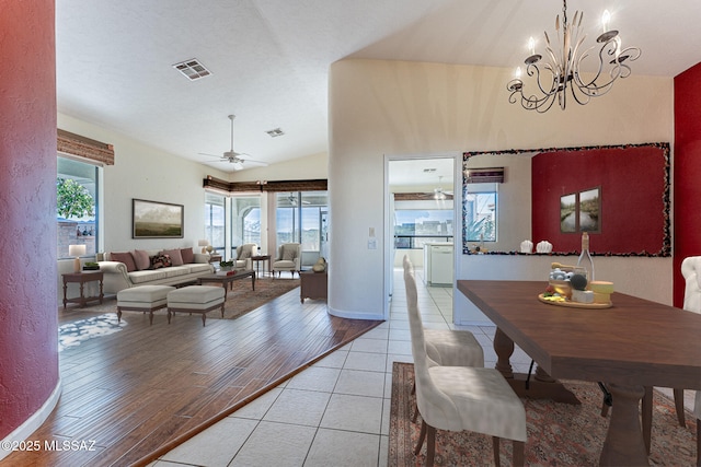 dining room with lofted ceiling, a healthy amount of sunlight, ceiling fan with notable chandelier, and light hardwood / wood-style flooring