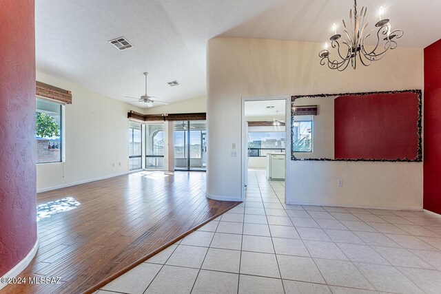 unfurnished room featuring vaulted ceiling, ceiling fan with notable chandelier, and light tile patterned floors