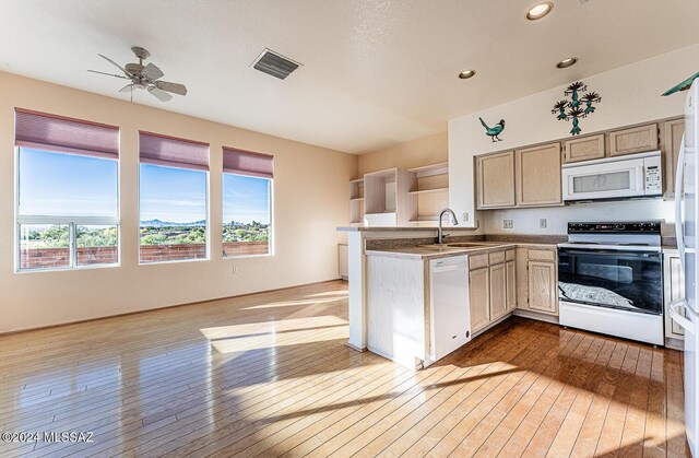 kitchen featuring light brown cabinetry, sink, kitchen peninsula, white appliances, and light hardwood / wood-style flooring