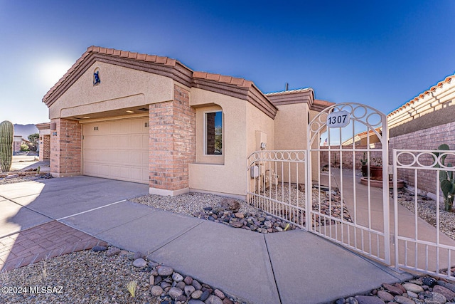 1307 W Mariquita St, Green Valley, AZ 85622 - view of side of home with driveway, stucco siding, an attached garage, and a gate