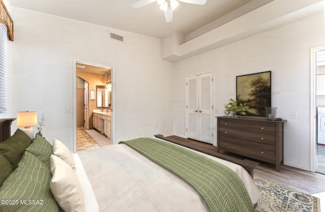 bedroom featuring ceiling fan, ensuite bathroom, light hardwood / wood-style floors, washer / clothes dryer, and a closet