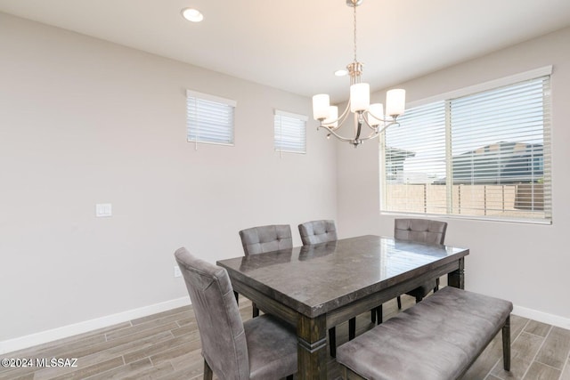 dining area featuring wood-type flooring, a healthy amount of sunlight, and a notable chandelier