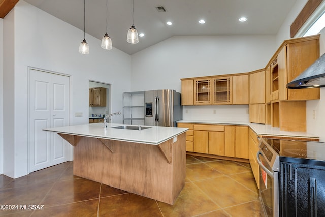 kitchen featuring tile patterned floors, stainless steel appliances, wall chimney range hood, sink, and a center island with sink