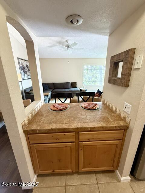 kitchen featuring light tile patterned floors, a textured ceiling, tile countertops, and ceiling fan