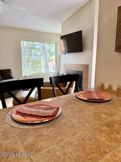 tiled dining space with ceiling fan, lofted ceiling, and a textured ceiling