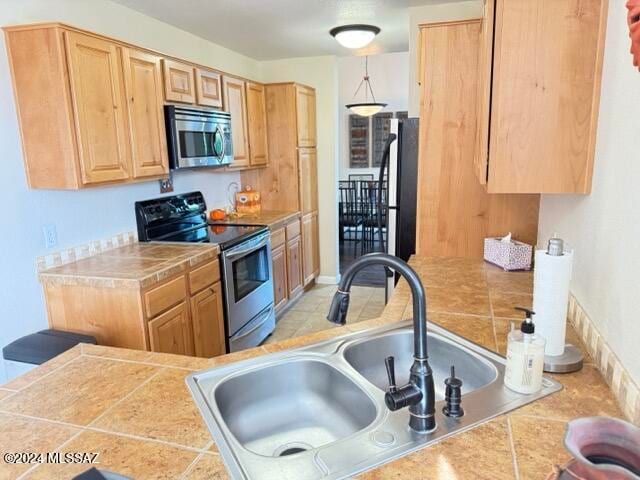 kitchen with tile counters, sink, and stainless steel appliances