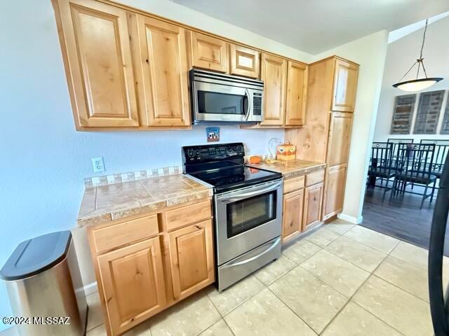 kitchen featuring decorative light fixtures, light tile patterned floors, and appliances with stainless steel finishes