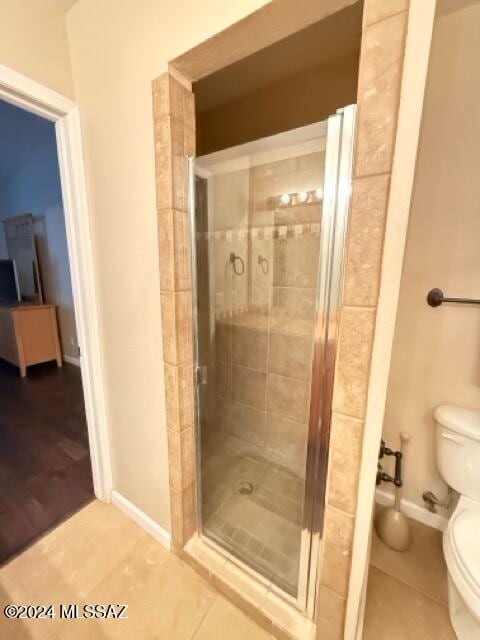 bathroom featuring toilet, wood-type flooring, and a shower with door