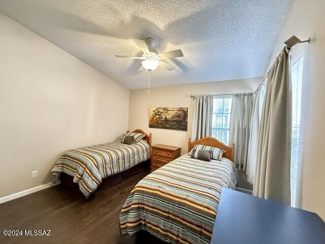 bedroom with a textured ceiling, dark hardwood / wood-style floors, and ceiling fan