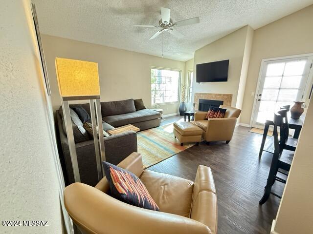 living room featuring a textured ceiling, dark hardwood / wood-style flooring, ceiling fan, and lofted ceiling